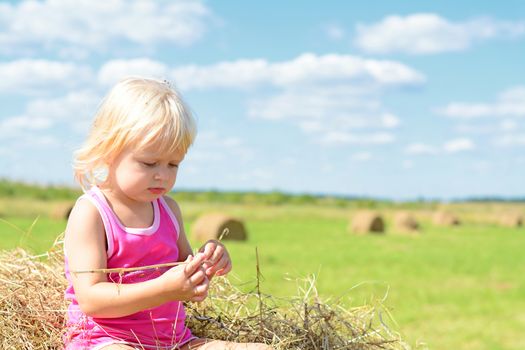 Rural Girl On The Straw After Harvest Field With Straw Bales