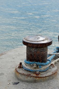 Rusty mooring bollard with ship ropes on seaport