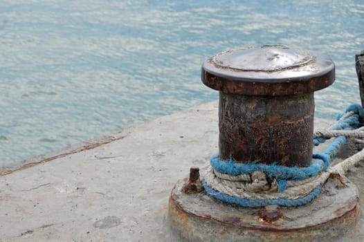 Rusty mooring bollard with ship ropes on seaport