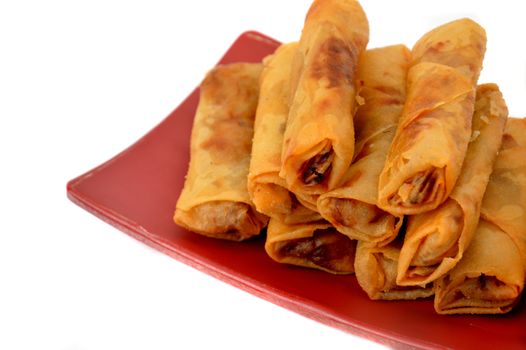 lumpia Semarang or Spring Rolls containing bamboo shoots and chicken on red plate at white background 