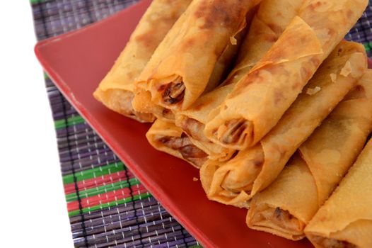 lumpia Semarang or Spring Rolls containing bamboo shoots and chicken on red plate at white background 