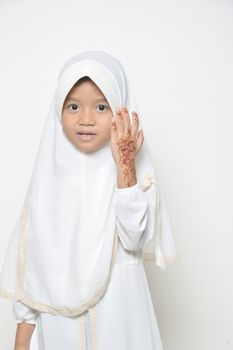 Moslem Asian little girl dressed with hijab in white with henna at her hand