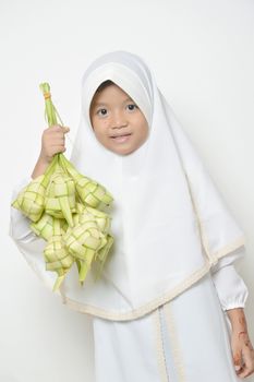 Moslem Asian little girl dressed with hijab in white holds ketupat