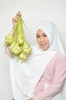 portrait of a beautiful muslim woman wearing a headscarf hold ketupat
