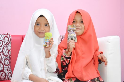 two Asian little girl Muslim showing results giving money visiting at Eid