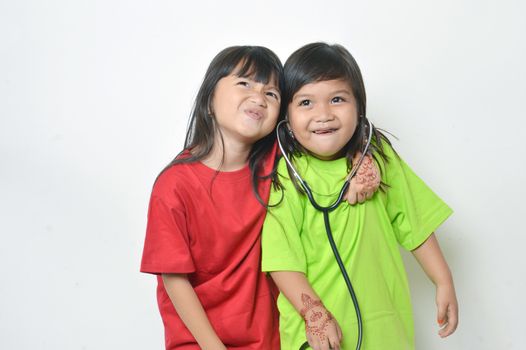 two asian little girl playing with a stethoscope