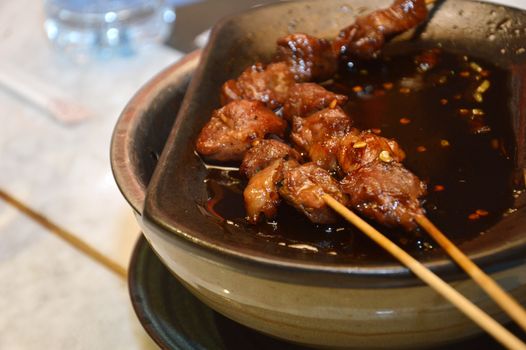 row of goat satay on hot plate