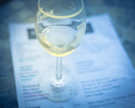 Close-up a glass of sweet white wine and tasting menu with price at local winery in North Texas, America