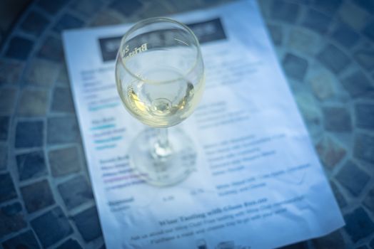 Close-up a glass of sweet white wine and tasting menu with price at local winery in North Texas, America