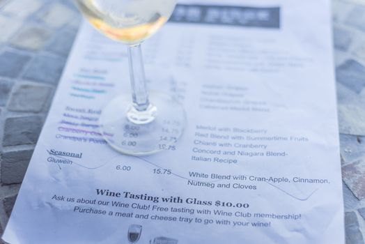 Close-up a glass of sweet white wine and tasting menu with price at local winery in North Texas, America