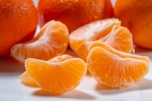 Several whole and peeled ripe tangerines on a white plate.