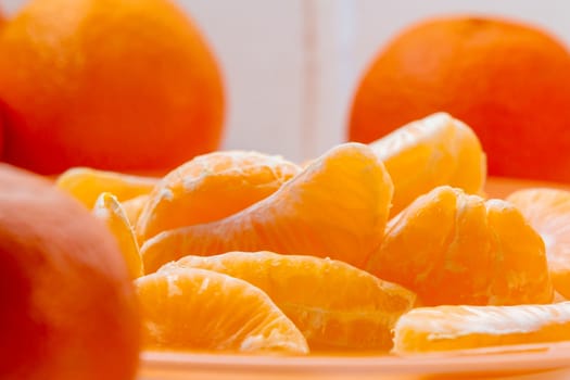 Several whole and peeled ripe tangerines on a orange plate.