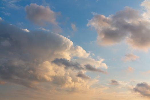 Beautiful cumulus clouds of unusual shape in the blue sky on a summer day.