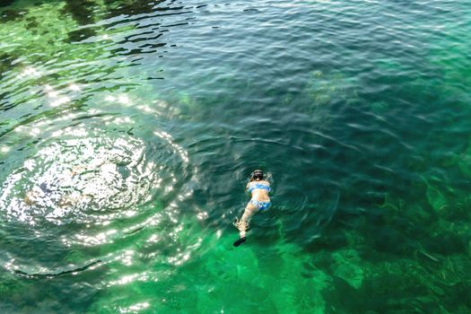 Girl dives with a mask while swimming in the turquoise sea water of the Gulf of Oman.