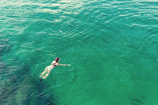 Girl dives with a mask while swimming in the turquoise sea water of the Gulf of Oman.