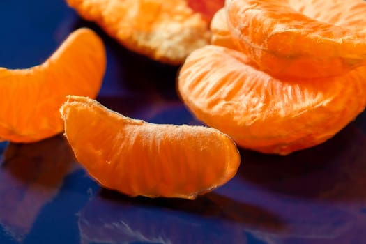 Several whole and peeled ripe tangerines on a blue plate.