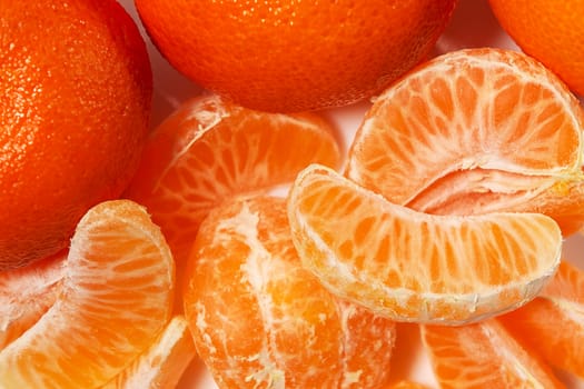 Several whole and peeled ripe tangerines on a white plate.