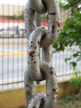 Close up of rusty chain links in foreground, with grid on background.
