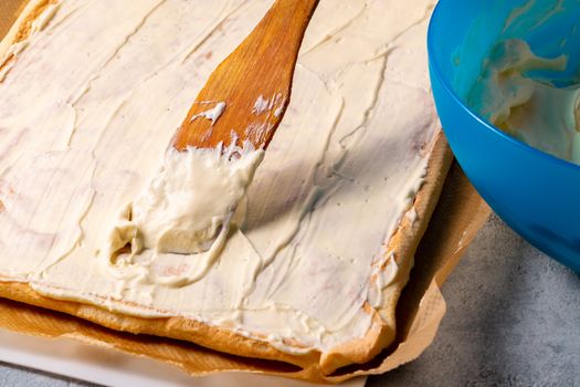 Smearing a baked roll cake with whipped butter cream.