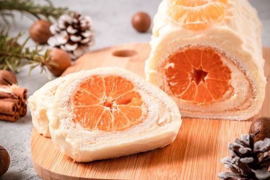 Sweet roll with whipped cream and tangerine filling and Christmas decorations.