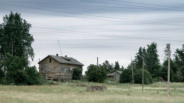 Old wooden house in the meadow. Stone foundation. Rural landscape.