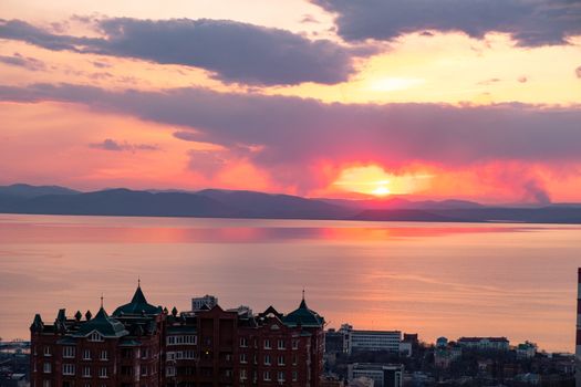 View of the city of Vladivostok from the hill eagle's nest . Sunset. The sky is orange and pink. Sea and city at sunset.