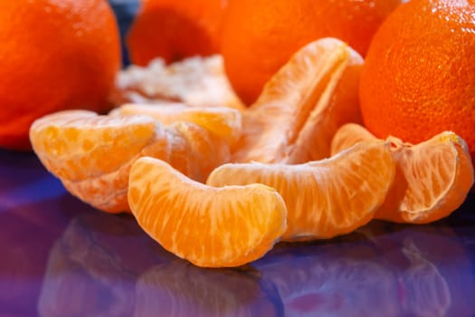 Several whole and peeled ripe tangerines on a blue plate.