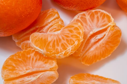 Several whole and peeled ripe tangerines on a white plate.