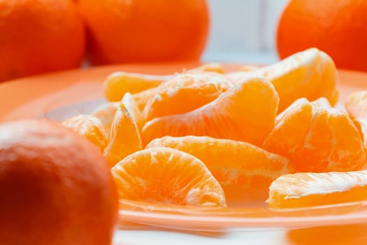 Several whole and peeled ripe tangerines on a orange plate.