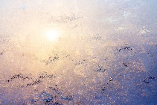 Nature background with ice pattern and sunlight on winter window.