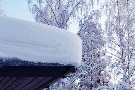 lot of snow on the roof of a rural cottage.