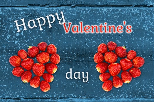 Beautiful greeting card with Valentines Day - hearts made from strawberries on the background of grunge wooden texture and the inscription Happy Valentine's Day