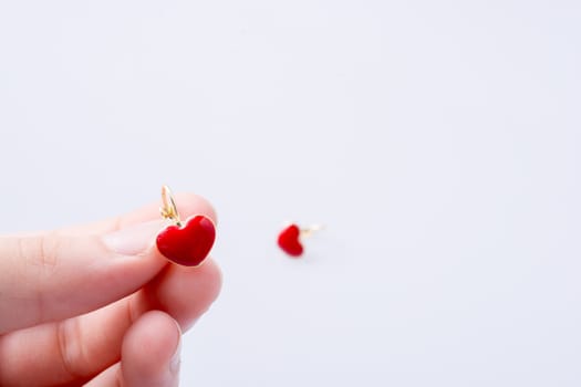 Red color heart shape earring in hand on white