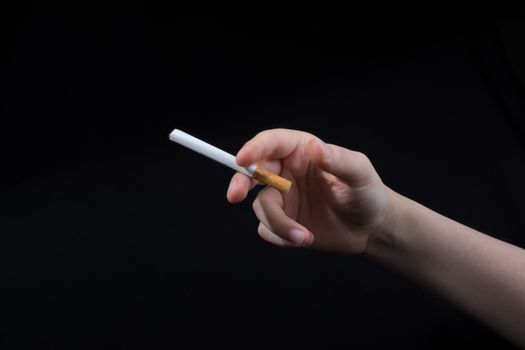 Hand is holding a cigarette on black background