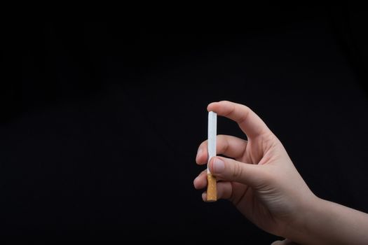 Hand is holding a cigarette on black background