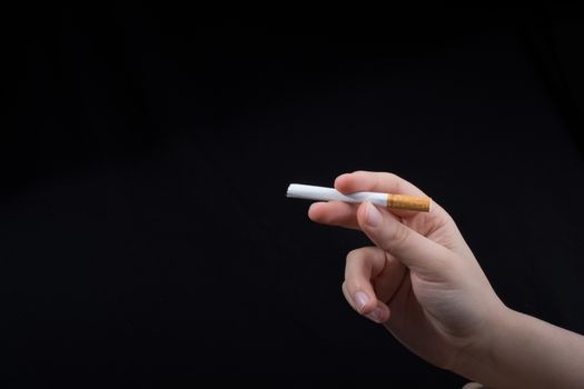 Hand is holding a cigarette on black background