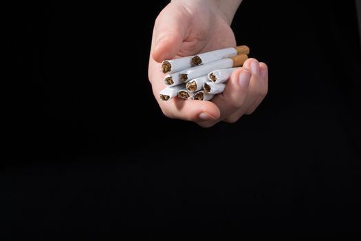 Hand is giving out cigarettes on a black background
