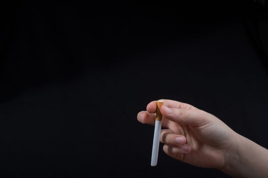 Hand is holding a cigarette on black background