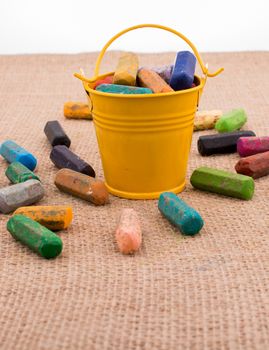 Crayons of various color in a bucket on a canvas