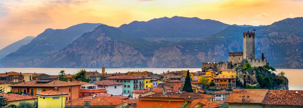 italian village skyline of Malcesine peaceful panoramic town on Garda Lake waterfront romantic horizontal panorama and idyllic picturesque castle .