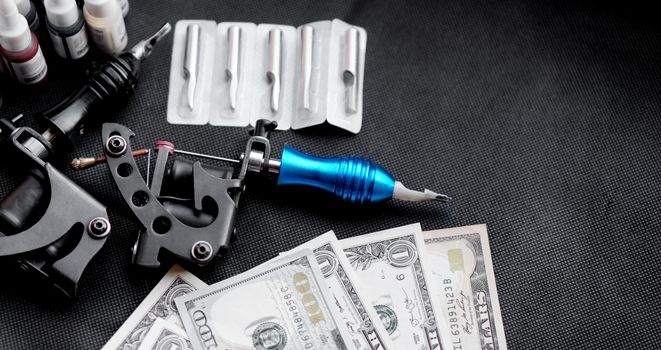 Tattoo machines on a black background and dollars. Tattoo art concept. Money for tattoo