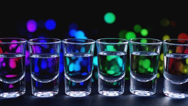 Glasses of vodka or tequila. In bar - neon background