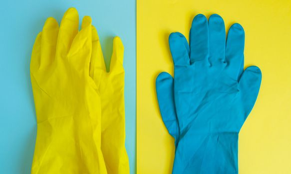 Flat lay of yellow and blue rubber protective gloves on double table background for spring or daily cleaning. The concept of a commercial cleaning company