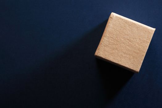 One brown cardboard cube on dark blue background