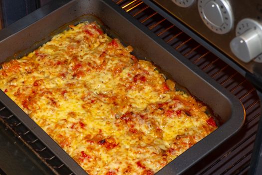 Freshly baked fish, meat and vegetable casserole with tomatoes and cheese.