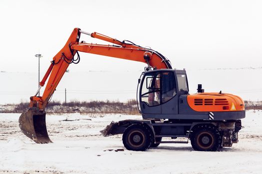 Excavator with a bucket standing in a snowy field.