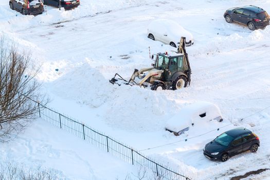 Tractor removes snow in the parking lot after a snowfall.