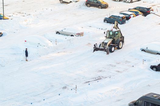 Tractor removes snow in the parking lot after a snowfall.