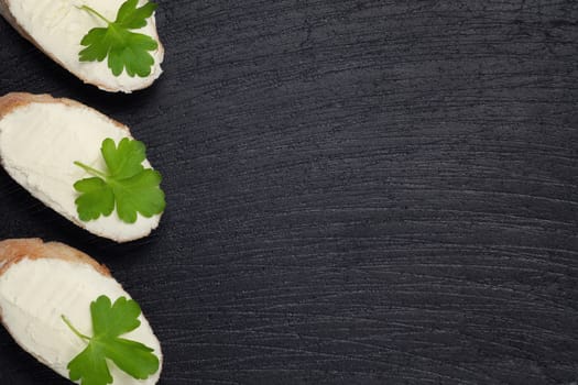 Sandwiches with cream cheese on a dark slate board - template for design with place for text.