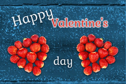 Beautiful greeting card with Valentines Day - hearts made from strawberries on the background of grunge wooden texture and the inscription Happy Valentine's Day